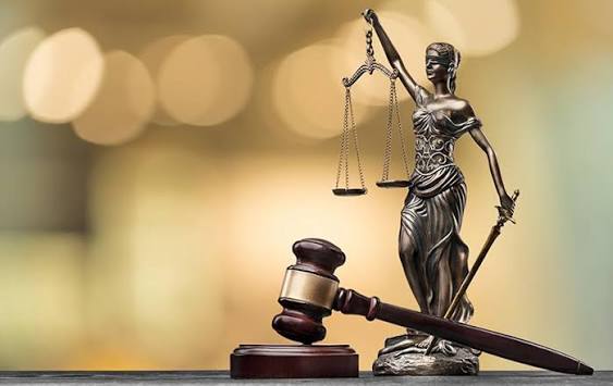Estátua da Justiça com balança ao lado de um martelo judicial.