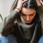 Pessoa expressando sofrimento emocional em contexto influenciado por experiências culturais e sociais.